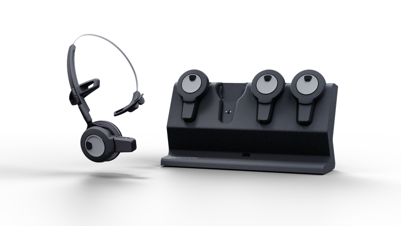 A black headset on a charging dock with three additional headsets.