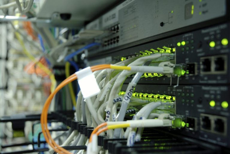 Close-up of network equipment with illuminated ports and connected cables.