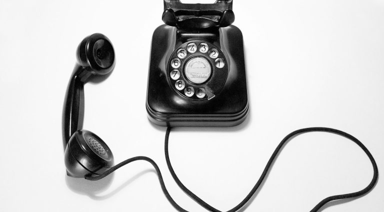 Kickstart Your Business with a Modern & Reliable On-Premise Phone System! Black vintage rotary telephone with a separate handset and coiled cord.