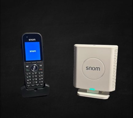 A Snom cordless phone on a charger next to a Snom base station.