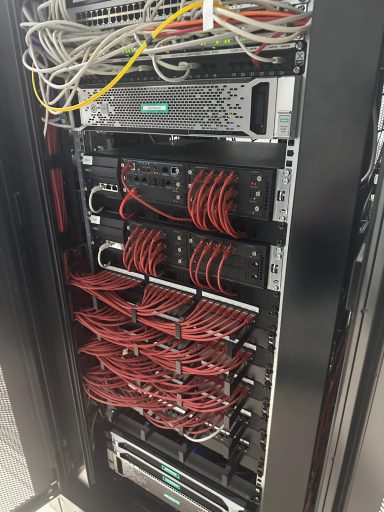 Close-up of a server rack with multiple servers and neatly arranged red cables.